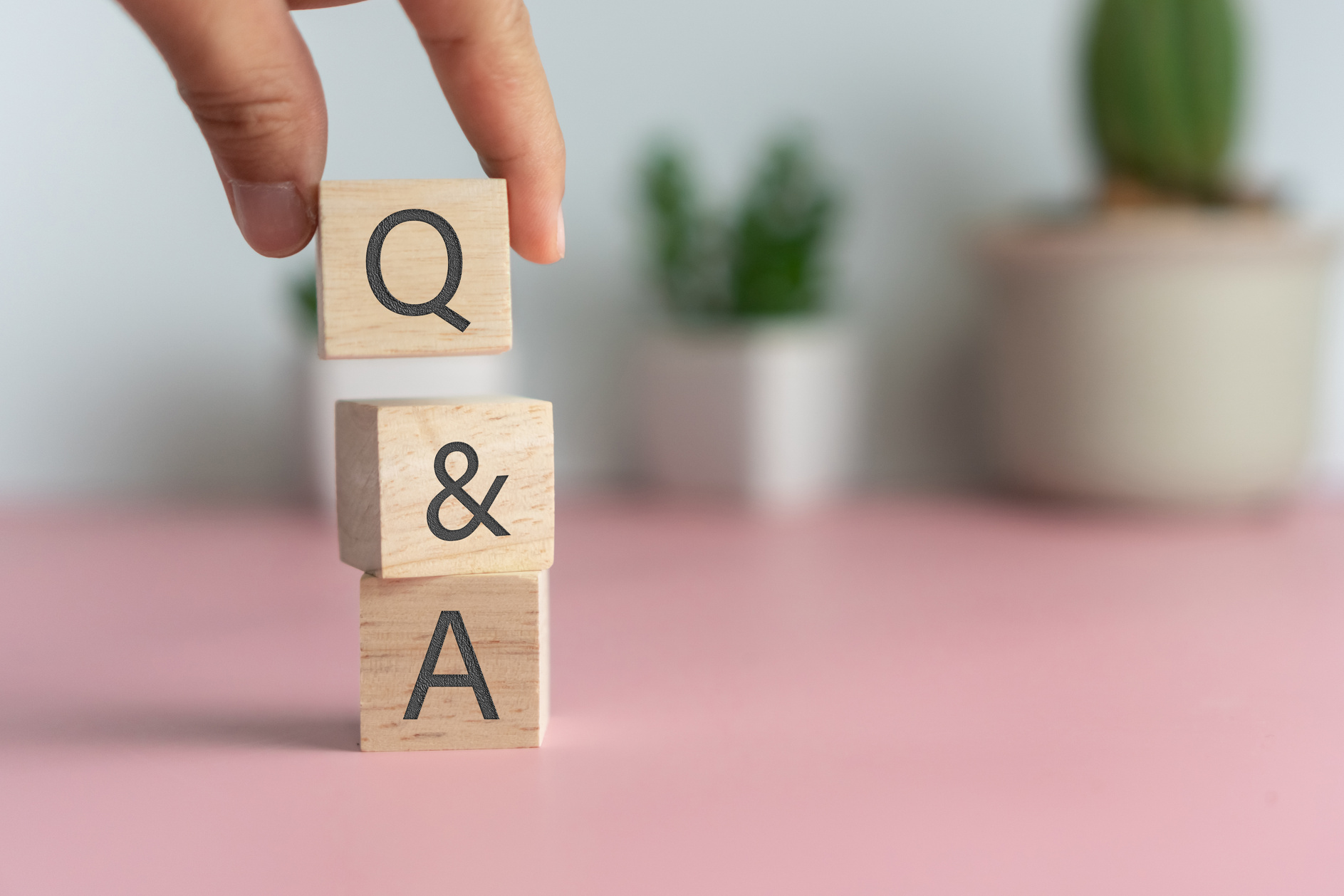 Person's Hand Stacking Wooden Blocks with Q and A Text